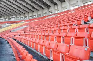 asientos vacíos de color naranja y amarillo en el estadio, filas de asientos en un estadio de fútbol foto