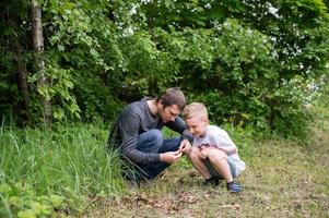 el chico es sentado siguiente a su papá, mirando a el suelo foto