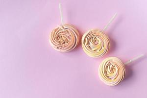 Pink round sweet meringues on a stick with decor lie on a pink background photo