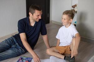 A cute boy in a white T-shirt collects an electrical designer with his dad in the room photo