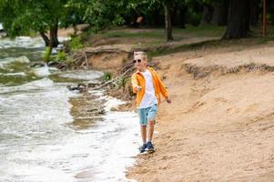 A boy in an orange shirt on the seashore photo