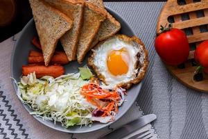 desayuno, frito huevos, frito embutido, vegetal ensalada y brindis en un marrón de madera mesa con café.