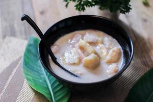 Banana in Coconut Milk on wood table Traditional dessert of asian, Thailand. photo