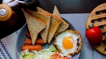 desayuno, frito huevos, frito embutido, vegetal ensalada y brindis en un marrón de madera mesa con café. foto