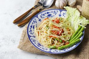 Somtum, Thai spicy papaya salad on white background, international Thai food Known and popular, made with papaya and tomatoes, it tastes sour, sweet and spicy. photo