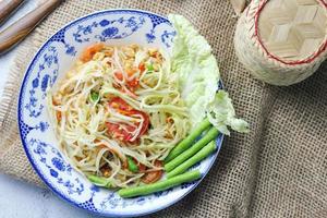 Somtum, Thai spicy papaya salad on white background, international Thai food Known and popular, made with papaya and tomatoes, it tastes sour, sweet and spicy. photo