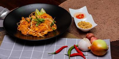 Thai Food Pad Thai Thai national dish Pad Thai on black plate with lime and seasonings. photo