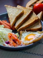 desayuno, frito huevos, frito embutido, vegetal ensalada y brindis en un marrón de madera mesa con café. foto