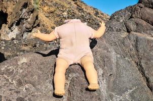 Toy doll laying on the rocks photo