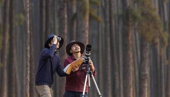 Team of the Asian naturalist looking at the new discovering bird species while exploring in the pine forest for surveying and locating the rare biological diversity and ecologist on the field study photo