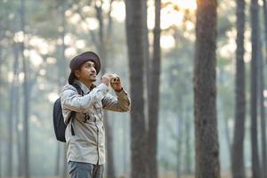 Bird watcher is looking through binoculars while exploring in the pine forest for surveying and discovering the rare biological diversity and ecologist on the field study concept photo