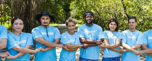 equipo de joven y diversidad voluntario trabajadores grupo disfrutar Caritativo social trabajo al aire libre en mangle plantando proyecto vistiendo azul camiseta mientras unión mano en montar unidad concepto foto