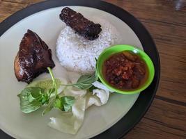 Close up photo of roasted chicken spicy with traditional sauce and rice on restaurant. The photo is suitable to use for food background, poster and food content.