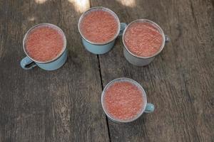 Close up photo of fresh strawberry juice on the blue cup at the garden shop. The photo is suitable to use for healthy drink, menu background, and drink content media.