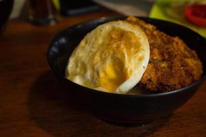 Fried eggs and chicken katsu in the rice bowl dishes menu on local mountain restaurant. The photo is suitable to use for traditional food background, poster and food content media.