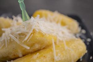 Close up photo of cheese fried banana with milk topping. The photo is suitable to use for Indonesia traditional food background, food poster and food content media.