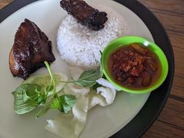 Close up photo of roasted chicken spicy with traditional sauce and rice on restaurant. The photo is suitable to use for food background, poster and food content.