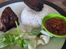 Close up photo of roasted chicken spicy with traditional sauce and rice on restaurant. The photo is suitable to use for food background, poster and food content.