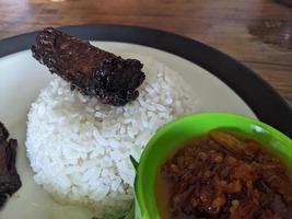 Close up photo of roasted chicken spicy with traditional sauce and rice on restaurant. The photo is suitable to use for food background, poster and food content.