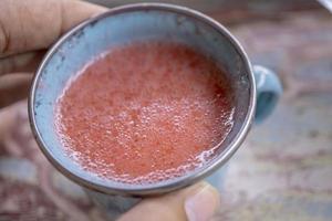 Close up photo of fresh strawberry juice on the blue cup at the garden shop. The photo is suitable to use for healthy drink, menu background, and drink content media.