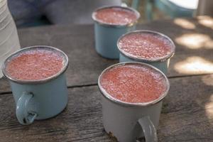 Close up photo of fresh strawberry juice on the blue cup at the garden shop. The photo is suitable to use for healthy drink, menu background, and drink content media.