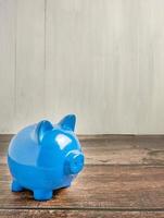 The blue piggy bank on wood table for earn or saving concept photo