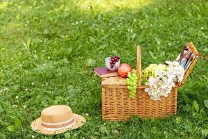 almuerzo en el parque en el verde césped. verano soleado día y picnic cesta. Copiar espacio foto