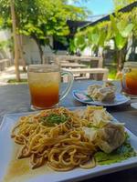 Noodle on white porcelain plate served outdoor with iced tea. Natural food closeup photography. photo