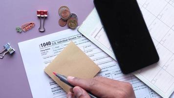 Writing tax due text on a sticky note with tax return form on table video