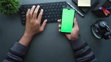 vista superior de la mano del hombre sosteniendo un teléfono inteligente con pantalla vacía en el escritorio de la oficina video