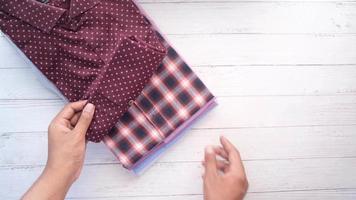 Young man's hand over stack of cloths on table, top view video