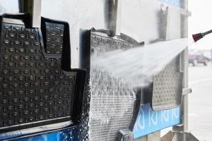 Cleaning car mat with high pressure water at car wash station photo