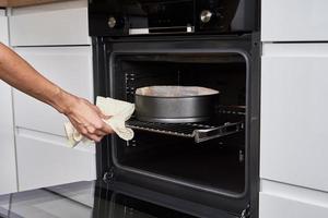 mujer cocinando pastel en horno eléctrico foto