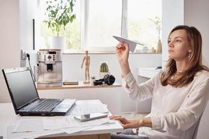 mujer juega con papel normal en la oficina en casa. procrastinar en el trabajo remoto foto