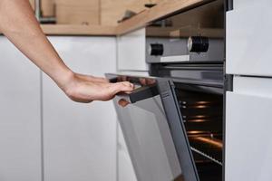 mujer abre la puerta del horno eléctrico foto