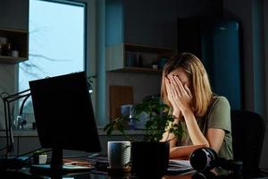 Tired woman works late at workplace in the night photo