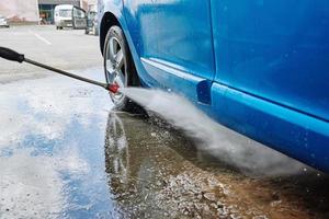 Cleaning car with high pressure water at car wash station photo