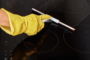 Woman in rubber gloves cleaning induction stove photo