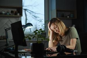 Tired woman works late at home workplace in the night photo