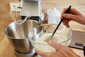 Woman pours flour into a mixer bowl photo