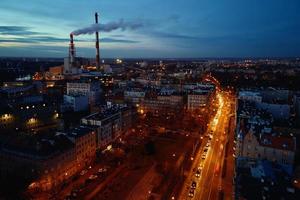 Steam from pipes over night city, aerial view photo