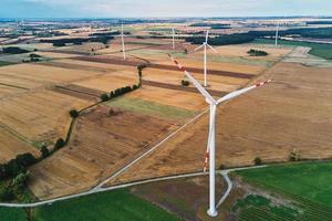 Windmill among agricultural fields. Wind turbine generator at summer day photo