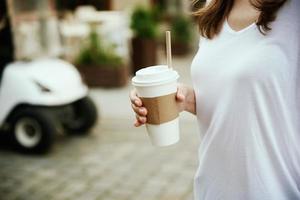 mujer sostiene una taza de café de papel en la calle de la ciudad foto