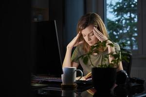 Woman working late remotely at home photo