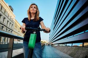 Woman rides on rental electric scooter at city photo