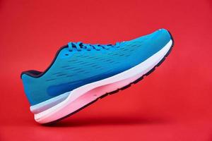 Blue running sneaker on red background, close up photo