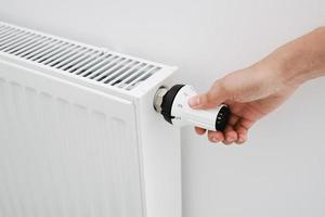 Woman hand adjusting temperature on heat radiator photo