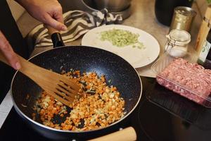 Woman cooking sauce bolognese in kitchen photo