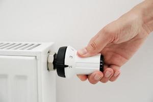 Woman hand adjusting temperature on heat radiator photo