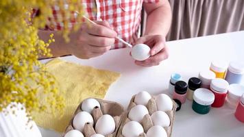 Young man coloring eggs sitting at the kitchen at home video